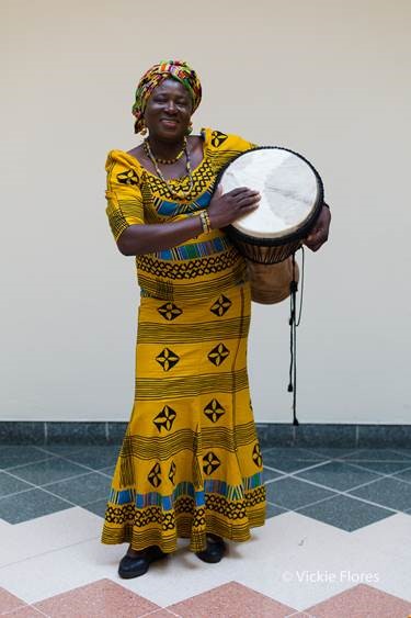 Woman in traditional clothing playing drum at a shopping centre event
