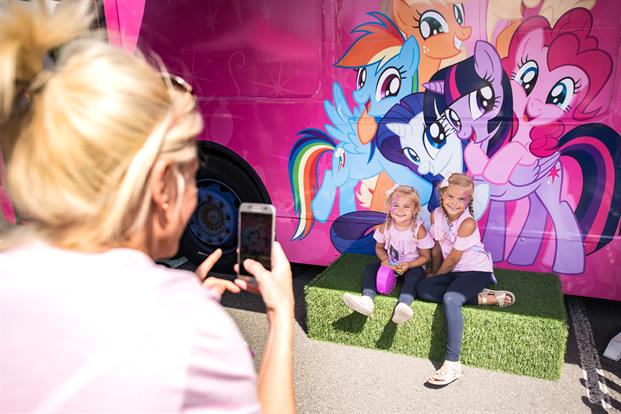 Children posing for a photo in front of a My Little Pony bus