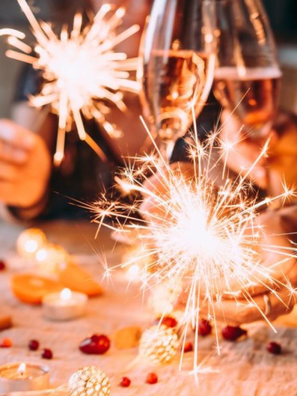 Friends celebrating Christmas or New Year's eve party with Bengal lights and rose champagne