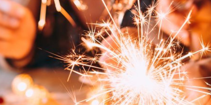 Friends celebrating Christmas or New Year's eve party with Bengal lights and rose champagne